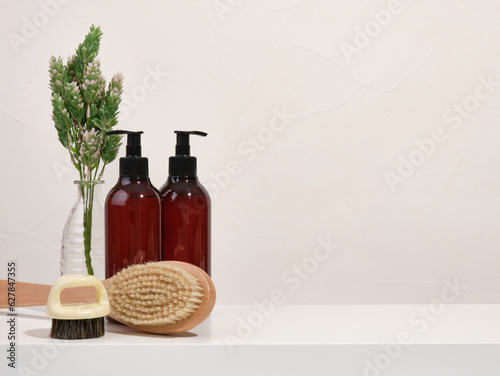 Wooden shower brush with a long handle and shampoos for hair care. Copy space for text. Eco friendly care.
