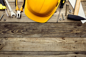 Happy Labor day USA national holiday greeting card template. Flat lay yellow hard hat, American flag, construction tools on wooden table. Top view.