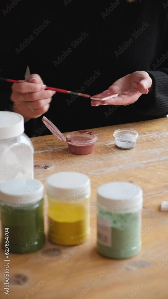 the potter applies a special liquid with a brush for baking the product. the potter applies a special liquid with a brush for patinating a beautiful teapot made by hand. potter at work