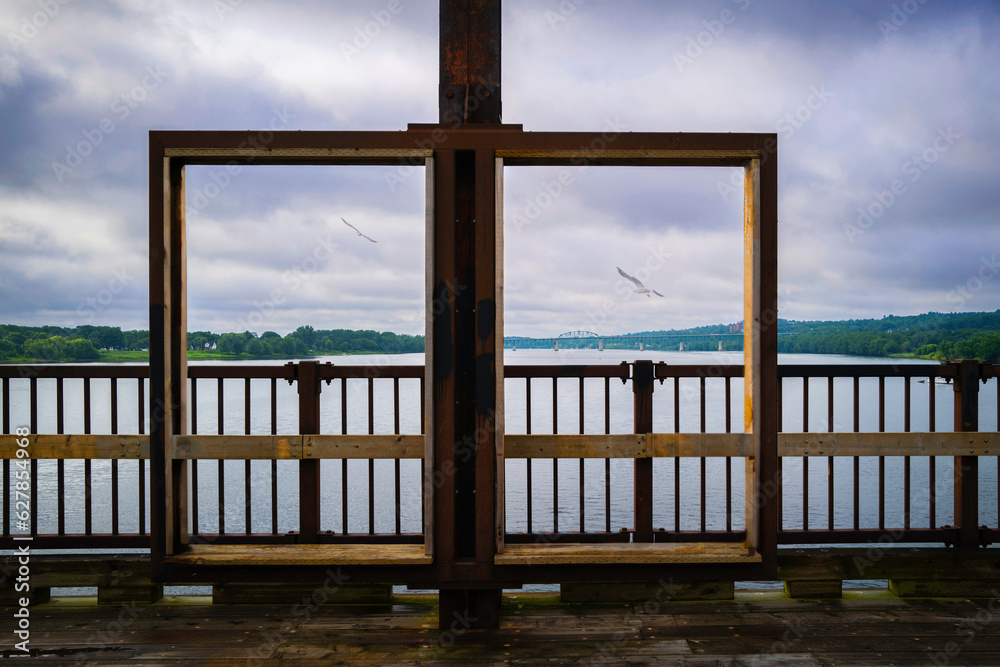 Rectangular frames over the Fredericton Railway Bridge on St John River in New Brunswick, Canada, dramatic cloudscape with seagulls flying