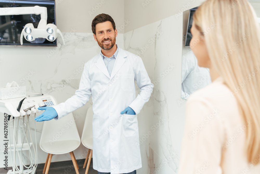 Obraz premium Smiling dental doctor in talking to attractive female patient with blonde hair in dental office