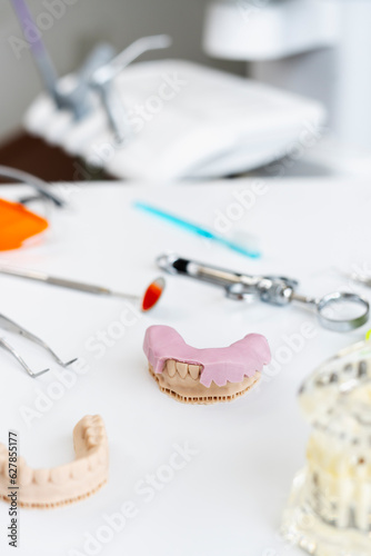 Dental office, cast of teeth, false teeth, implants, dental tools on workplace. Modern office