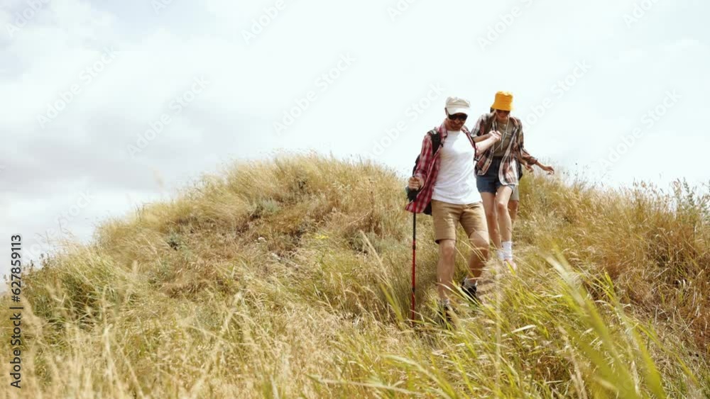 Young active people, friends, men and women going hiking, carefully walking down the hill on warm summer day. Concept of active lifestyle, friendship, summertime, hobby, leisure activity Young active people, friends, men and women going hiking, carefully walking down the hill on warm summer day. Concept of active lifestyle, friendship, summertime, hobby, leisure activity