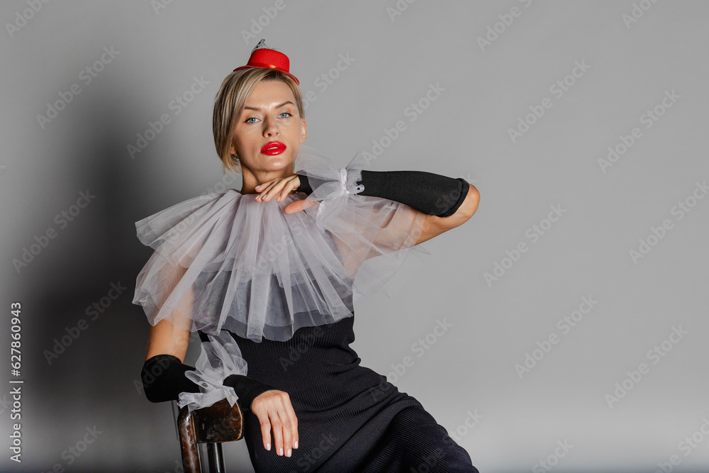 Elite clown. Woman dressed as clown iblack dress with harlequin collar and red hat. Contrast image on grey background. High quality photo Elite clown. Woman dressed as clown iblack dress with harlequin collar and red hat. Contrast image on grey background. High quality photo