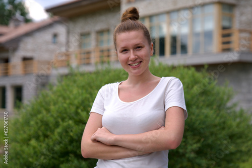 Portrait of happy young woman standing in the garden outside her luxury home and smiling and relax outside 