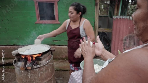 Two adult Hispanic women having fun while preparing corn tortillas