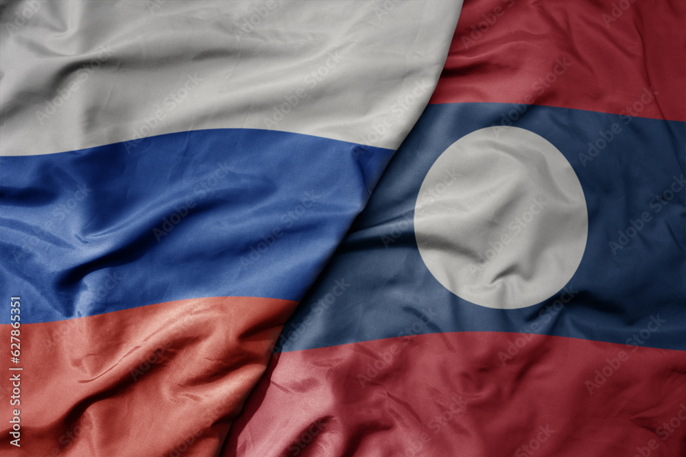Fototapeta premium big waving realistic national colorful flag of russia and national flag of laos .