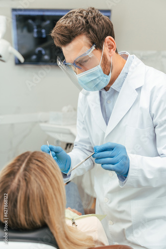 Portrait of professional attractive middle aged male dentist in protective mask and glasses