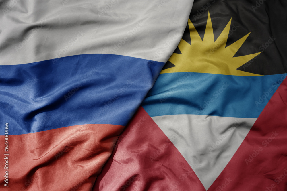 Fototapeta premium big waving realistic national colorful flag of russia and national flag of antigua and barbuda .