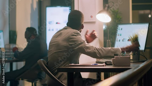 African american employee pissed about noisy coworker listening to music and pretending to beat drums in office. Businessman frustrated with overzealous colleague banging desk