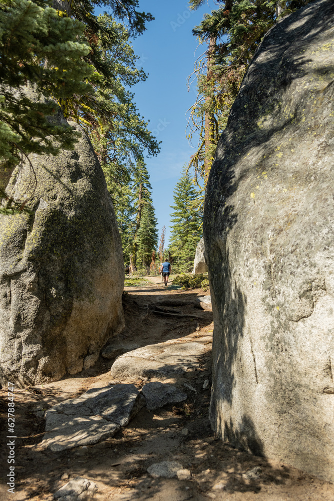 Woman Hikes on Trail Through Large Boulders in Yosemite Woman Hikes on Trail Through Large Boulders in Yosemite