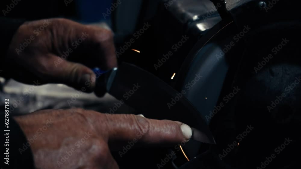 Men's hands work at a machine. Sparks fly from the hot metal. Man worked hard on steel. Machine sharpening on an electric grinder, manual sharpening on a rotary grinding stone, close-up. Men's hands work at a machine. Sparks fly from the hot metal. Man worked hard on steel. Machine sharpening on an electric grinder, manual sharpening on a rotary grinding stone, close-up.