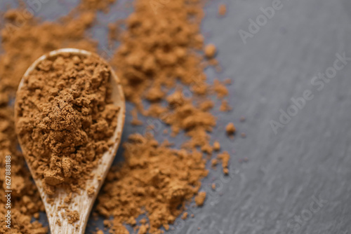 Guarana natural biostimulant. Guarana powder in a wooden spoon on a black slate background.Natural tonic. Alternative medicine and homeopathy.Supplements and vitamins. sports nutrition.  photo