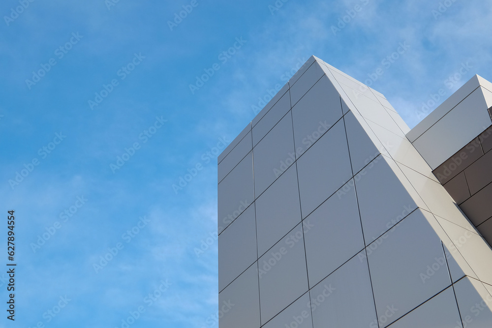 The exterior wall of a contemporary commercial style building with aluminum metal composite panels in various shapes. The futuristic building has engineered diagonal cladding steel frame panels. The exterior wall of a contemporary commercial style building with aluminum metal composite panels in various shapes. The futuristic building has engineered diagonal cladding steel frame panels.