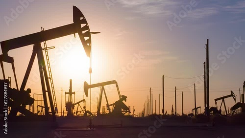 The sun rises behind a large oil field in California.