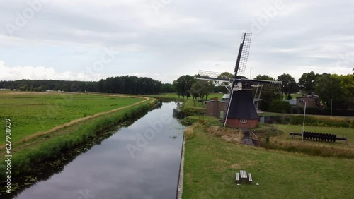 Aerial view traveling out over the water mill and passing through a small wooden bridge. In the town of De Groeve, the Netherlands. photo