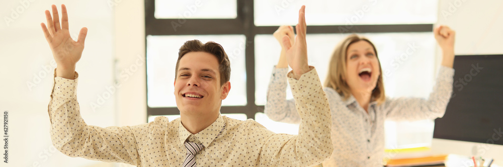 Fototapeta premium Business partners rejoicing and raising their hands up in office