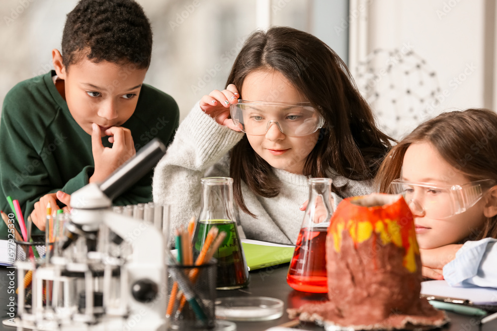Little children conducting chemistry experiment in science classroom