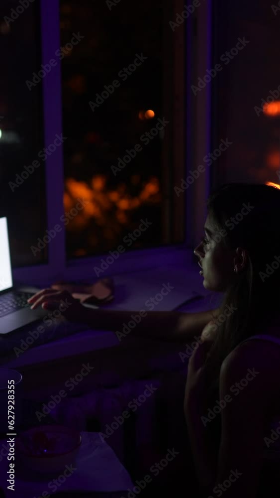 A young woman is working on her laptop and talking late at night. A young woman is working on her laptop and talking late at night.