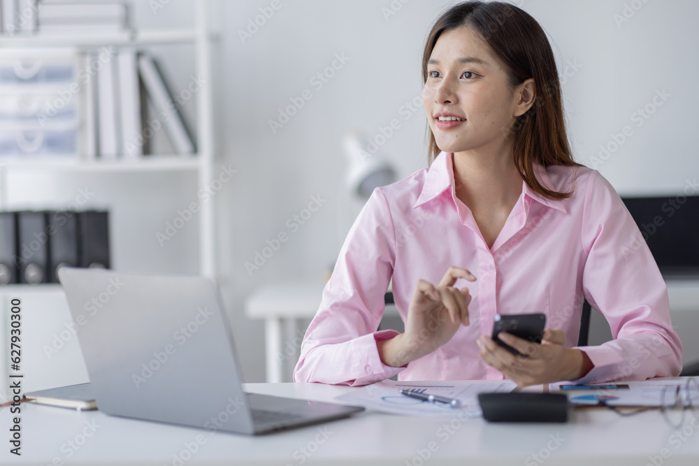 Asian Woman entrepreneur busy with her work in the office. Young Asian woman talking over smartphone or cellphone while working on computer at her desk.
Asian Woman entrepreneur busy with her work in the office. Young Asian woman talking over smartphone or cellphone while working on computer at her desk.