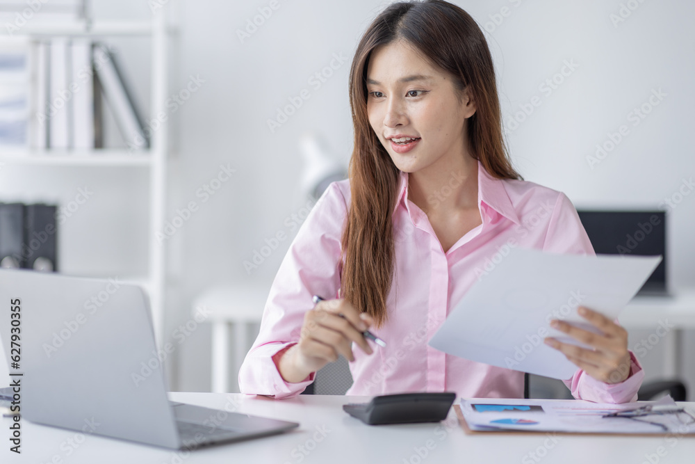 Asian Businesswoman Using laptop computer and working at office with calculator document on desk, doing planning analyzing the financial report, business plan investment, finance analysis concept.
Asian Businesswoman Using laptop computer and working at office with calculator document on desk, doing planning analyzing the financial report, business plan investment, finance analysis concept.