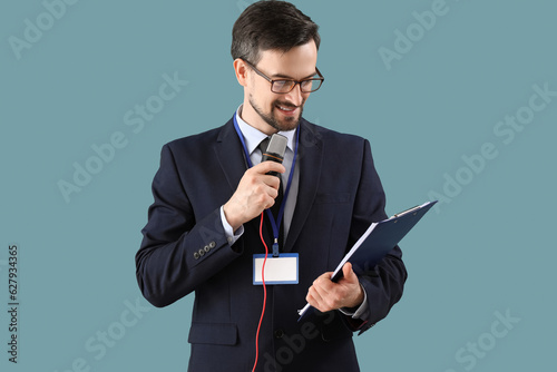 Male journalist with microphone and clipboard on blue background