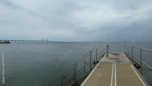 A walk along a small pier near near Sibbarp, Malmo, Sweden. In the background can be seen the Oresund Bridge. Handheld dolly forward shot photo