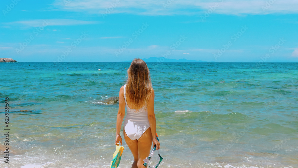 Sensual young woman holds snorkel mask and fins, ready for underwater snorkeling. Thailand travel, summer vibes. Concept of beach vacation and water adventure. Sensual young woman holds snorkel mask and fins, ready for underwater snorkeling. Thailand travel, summer vibes. Concept of beach vacation and water adventure.