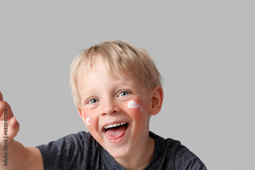Allergic little boy with sunburned face and cream on grey background, closeup Allergic little boy with sunburned face and cream on grey background, closeup