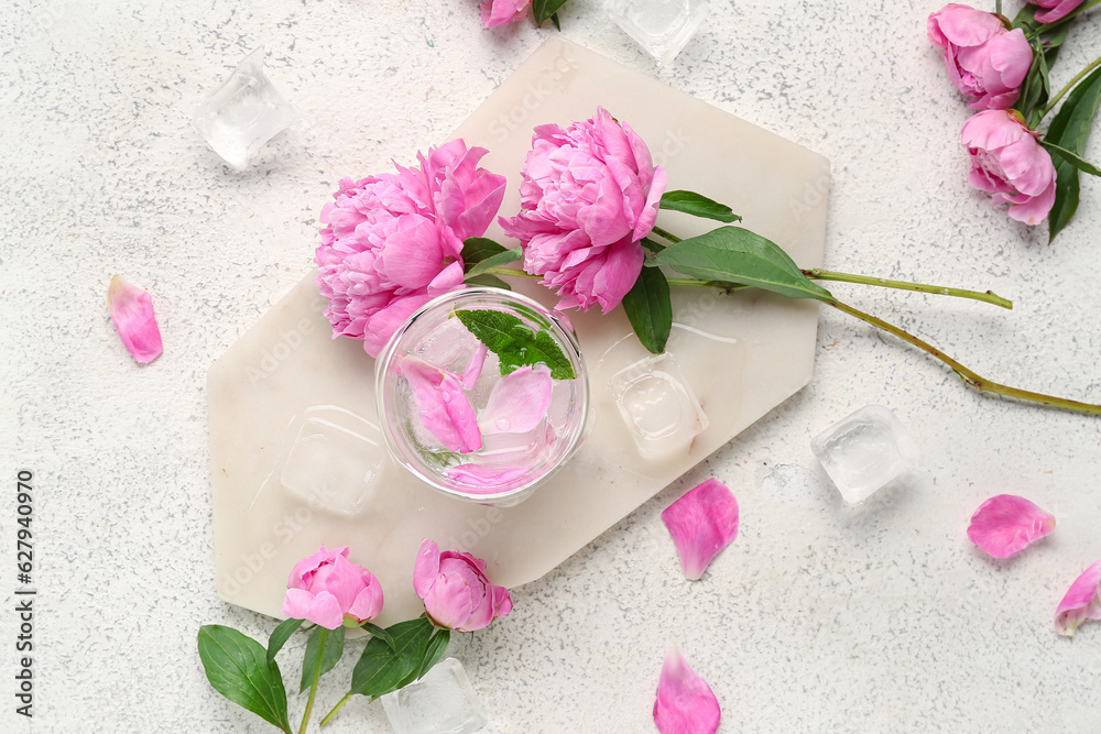Composition with glass of water, ice cubes and beautiful peony flowers on light background Composition with glass of water, ice cubes and beautiful peony flowers on light background