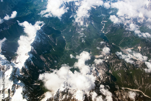 Beautiful window view of fluffy clouds and Alps mountains from passenger seat on airplane. Travel and air transportation