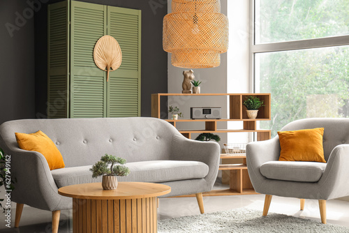 Interior of modern living room with grey sofa, armchair and wooden coffee table
