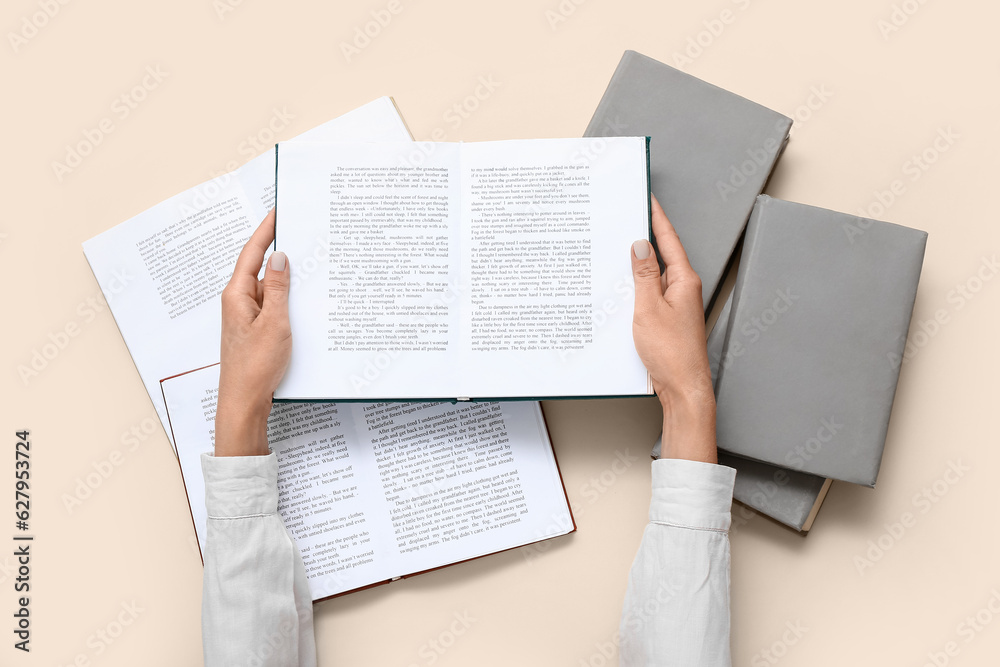 Fototapeta premium Female hands holding open book on beige background