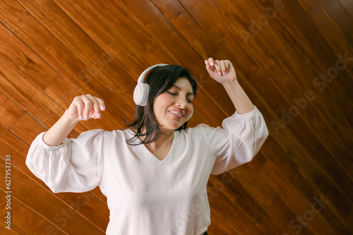Portrait of cute hispanic girl using headphones and listening to music