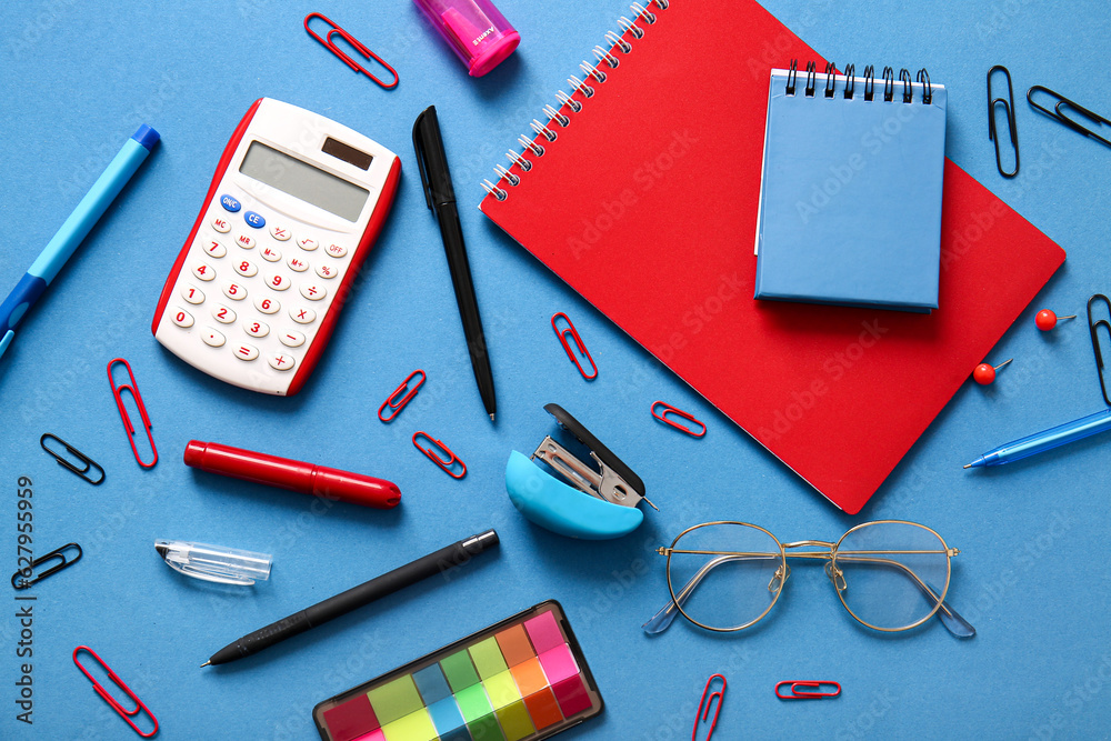 Different school stationery, notebooks and glasses on blue background Different school stationery, notebooks and glasses on blue background