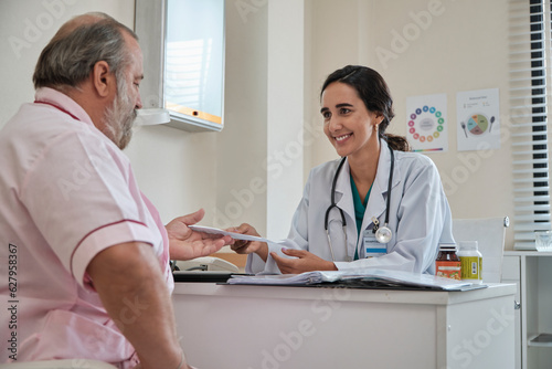 Female doctor and professional nutritionist in uniform advise Caucasian patients about supplementary foods and nutrients for healthy diet at clinic hospital, checkups, and appointments. photo