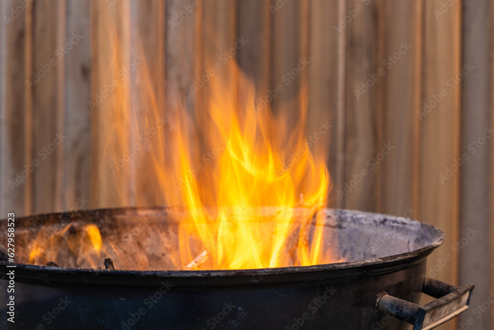 Black metal round barbeque with fire for a picnic is in the terrace Black metal round barbeque with fire for a picnic is in the terrace