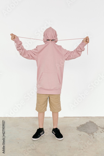 Picture of preteen boy tightening lace to hide his face in hood 