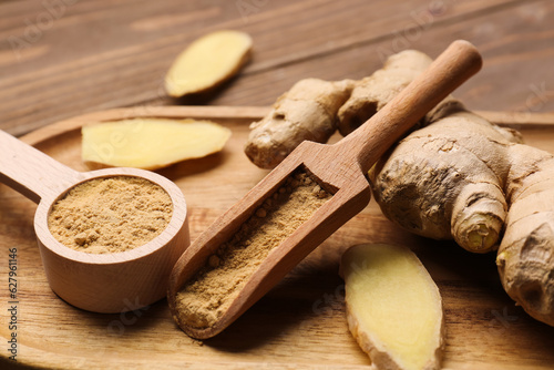 Fresh ginger root, spoon and scoop with dried powder on wooden background