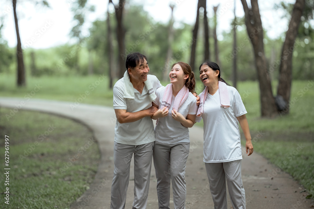 Beautiful Asian woman taking her father and mother to exercise in the park happily, with a smile. Young woman invites parents to exercise, warm family, good health. concept health care life insurance. Beautiful Asian woman taking her father and mother to exercise in the park happily, with a smile. Young woman invites parents to exercise, warm family, good health. concept health care life insurance.