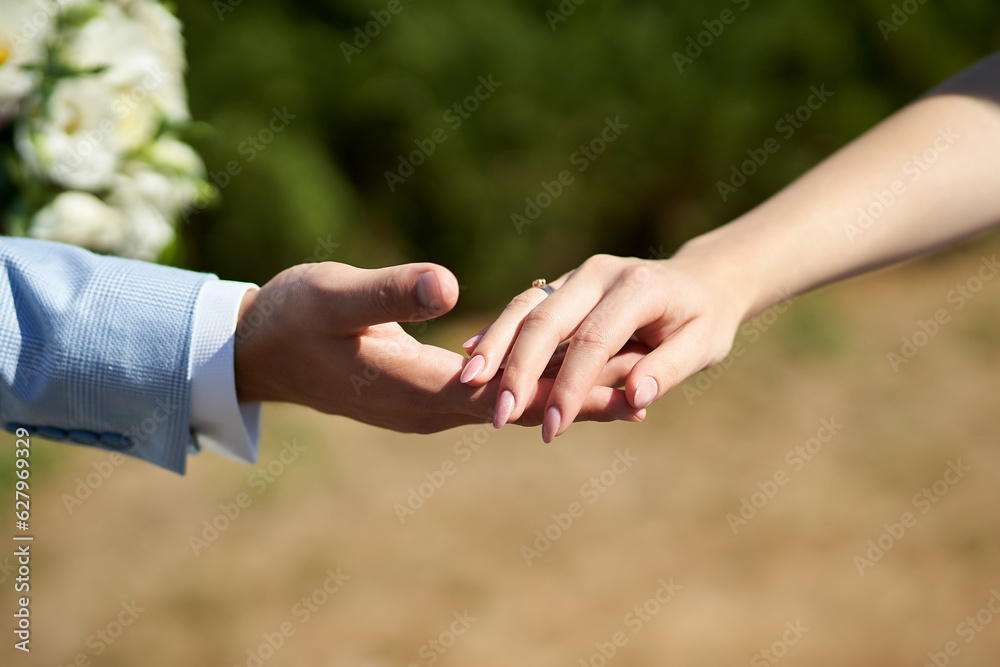 Close-up photo of the hands of the newlyweds, the bride and groom, holding each other Close-up photo of the hands of the newlyweds, the bride and groom, holding each other