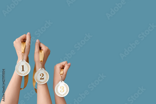 Fototapeta Naklejka Na Ścianę i Meble -  Female hands with medals on blue background