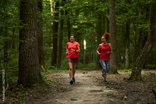 Fototapeta Naklejka Na Ścianę i Meble -  Happy ladies jogging in the forest