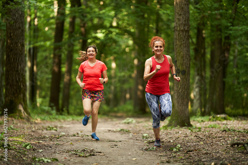 Happy ladies jogging in the forest