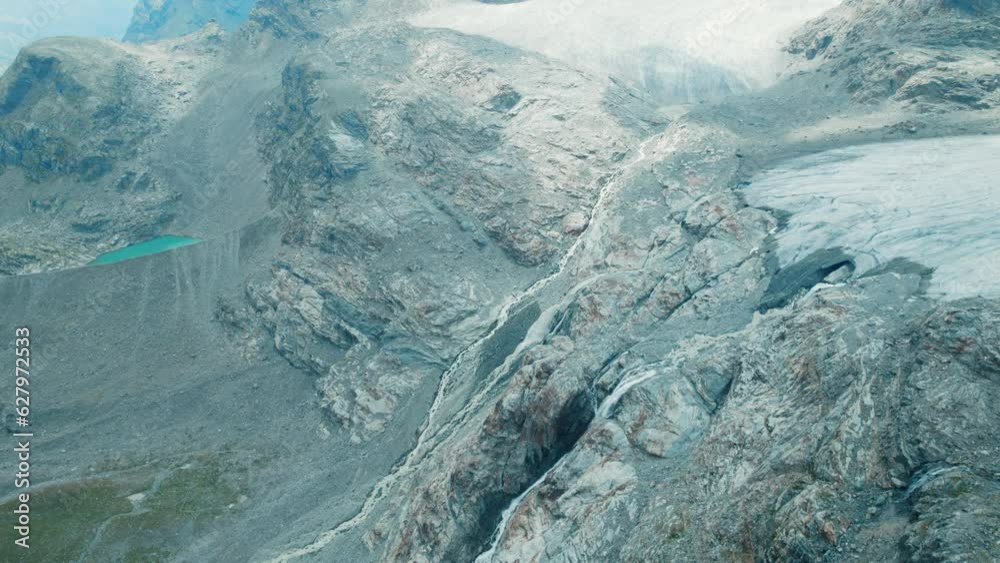 Giant waterfall coming from a Glacier Melting in a lake below due to Climate Change in the Alps, Fellaria Big Waterfalls come down from the glaciers edge, top down view of the mountains and lake below Giant waterfall coming from a Glacier Melting in a lake below due to Climate Change in the Alps, Fellaria Big Waterfalls come down from the glaciers edge, top down view of the mountains and lake below