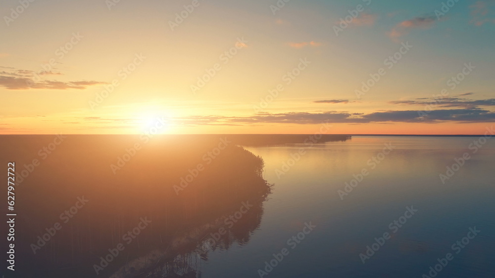 Aerial Drone View: Beautiful sunset over water and forest. Magestic landscape. Kiev Sea, Ukraine, Europe. Travel and tourism background. Warm orange toning filter.