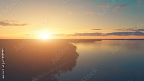 Aerial Drone View: Beautiful sunset over water and forest. Magestic landscape. Kiev Sea, Ukraine, Europe. Travel and tourism background. Warm orange toning filter. © Goinyk