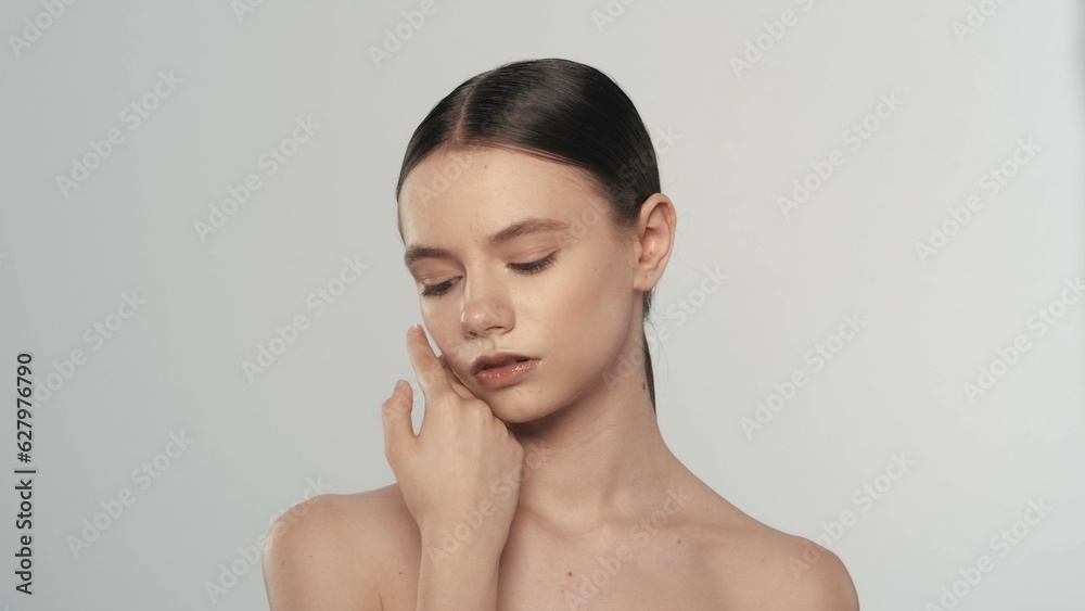 Beautiful brunette model with perfect skin and closed eyes touching her cheek Beautiful brunette model with perfect skin and closed eyes touching her cheek