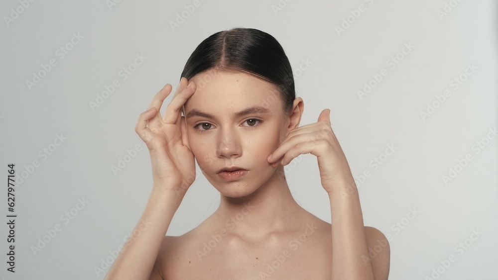 Attractive female model with arms up touching her face looking at the camera Attractive female model with arms up touching her face looking at the camera