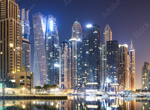Promenade and canal in Dubai Marina at night with luxury skyscrapers around United Arab Emirates